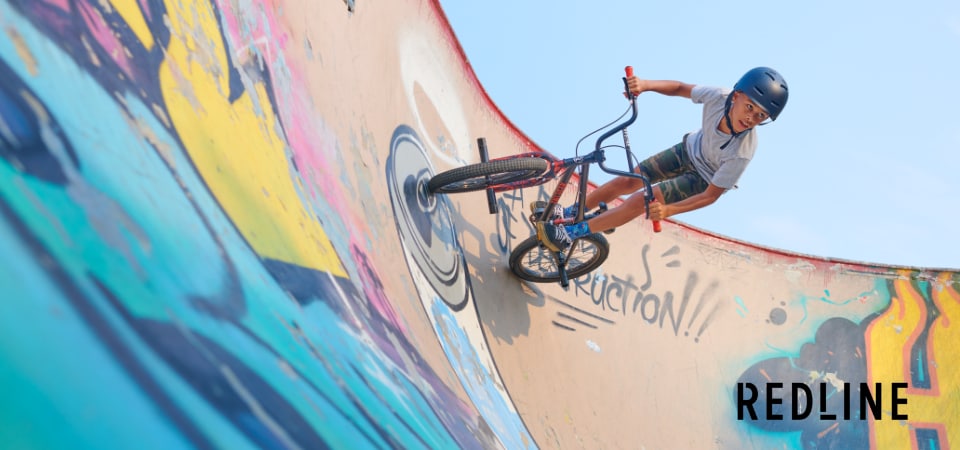 A boy riding a Redline BMX bike on an outdoor ramp.