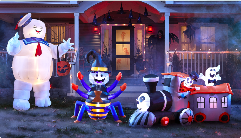Inflatable ghost, skeleton dragon and a ghoul lit up on a foggy lawn in front of a home.