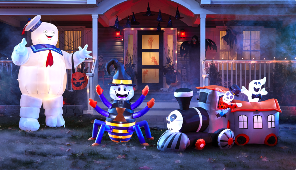 Bonhomme guimauve Stay Puft gonflable Gemmy, araignée heureuse gonflable For Living et train effrayant devant une maison décorée pour l’Halloween.