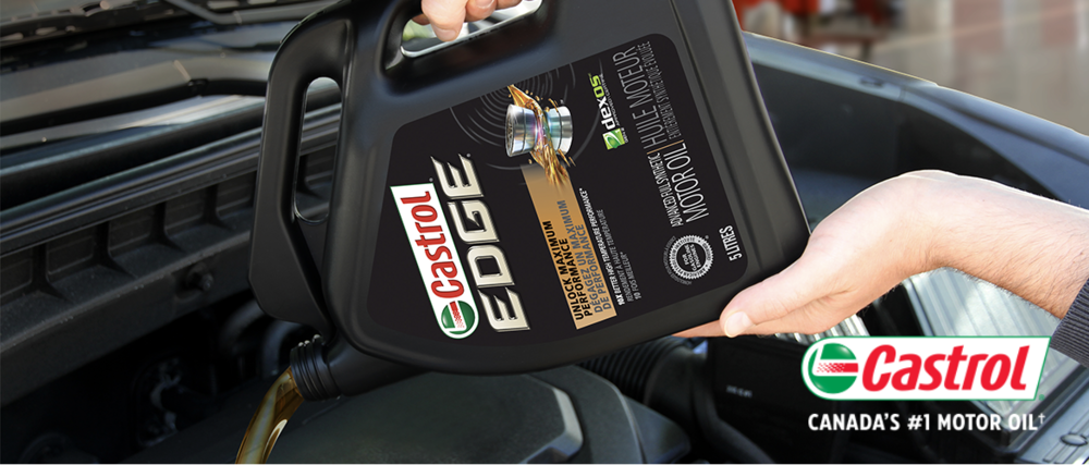 A jug of Castrol EDGE motor oil being poured into an engine’s oil reservoir.