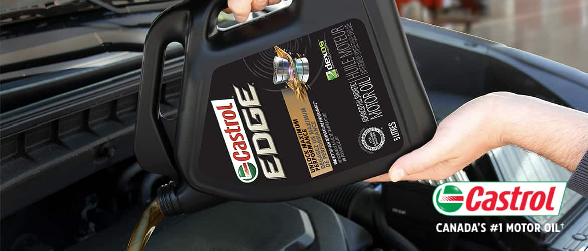 A bottle of Castrol EDGE Advanced Full Synthetic motor oil being poured into an engine’s oil reservoir.