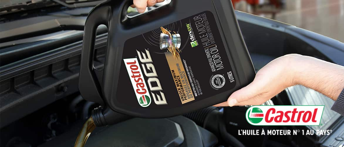 Une bouteille d'huile moteur entièrement synthétique Castrol EDGE versée dans le réservoir d'un moteur.