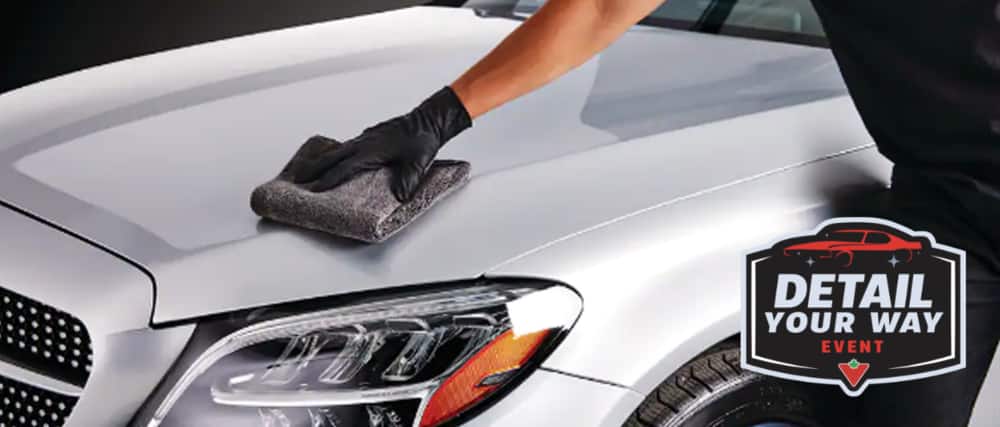 A hand wearing a nitrile glove wipes a car hood with a SIMONIZ Microfibre Towel.
