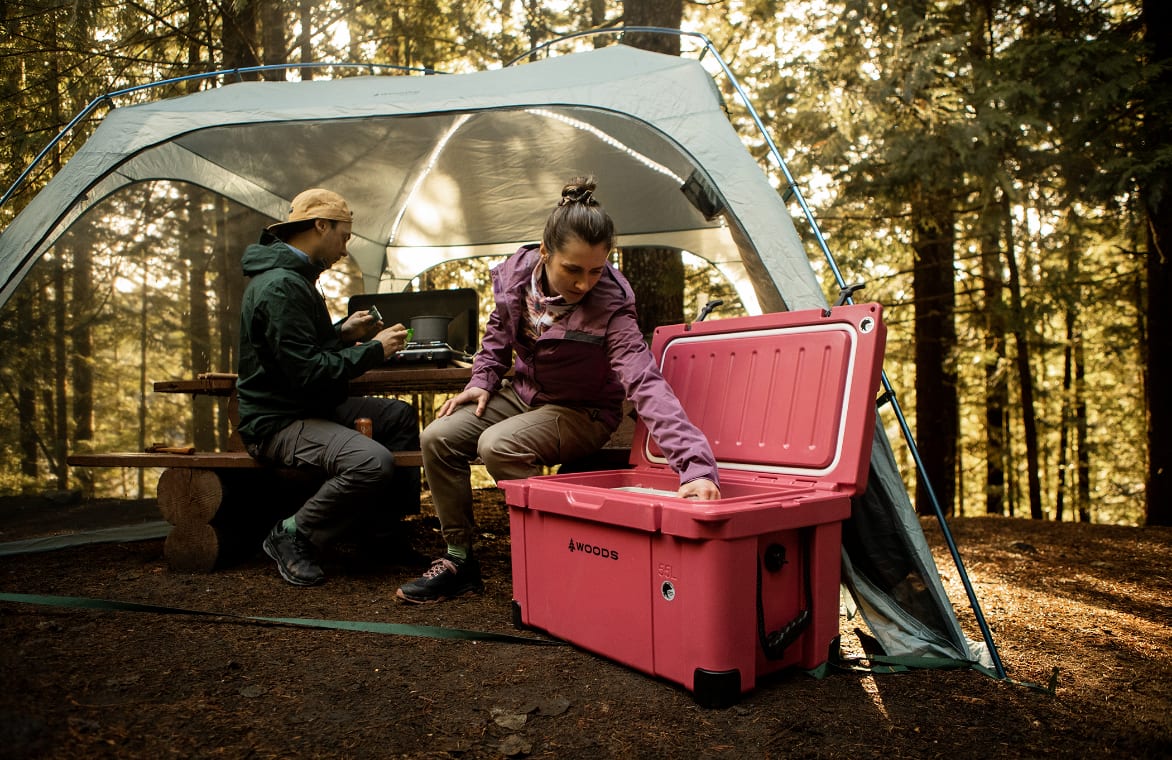 Woman reaching into a Woods cooler at a campsite