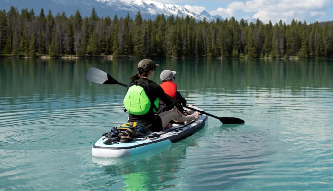 An adult and a child riding in a kayak in a lake.