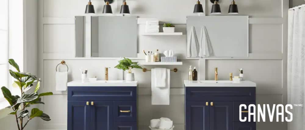 Two CANVAS Milford single sink vanities in a bathroom setting, painted navy blue with white ceramic tops and gold-finish faucets.