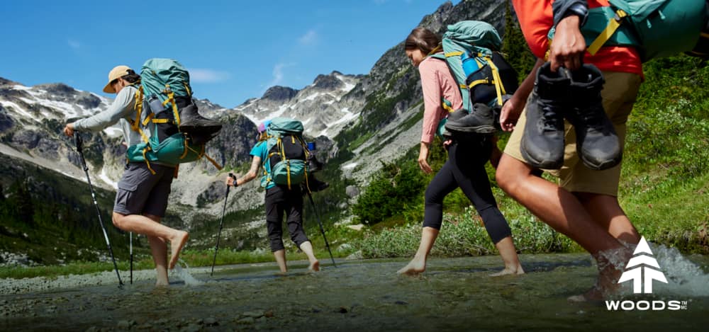 Group of hikers walking barefoot through water