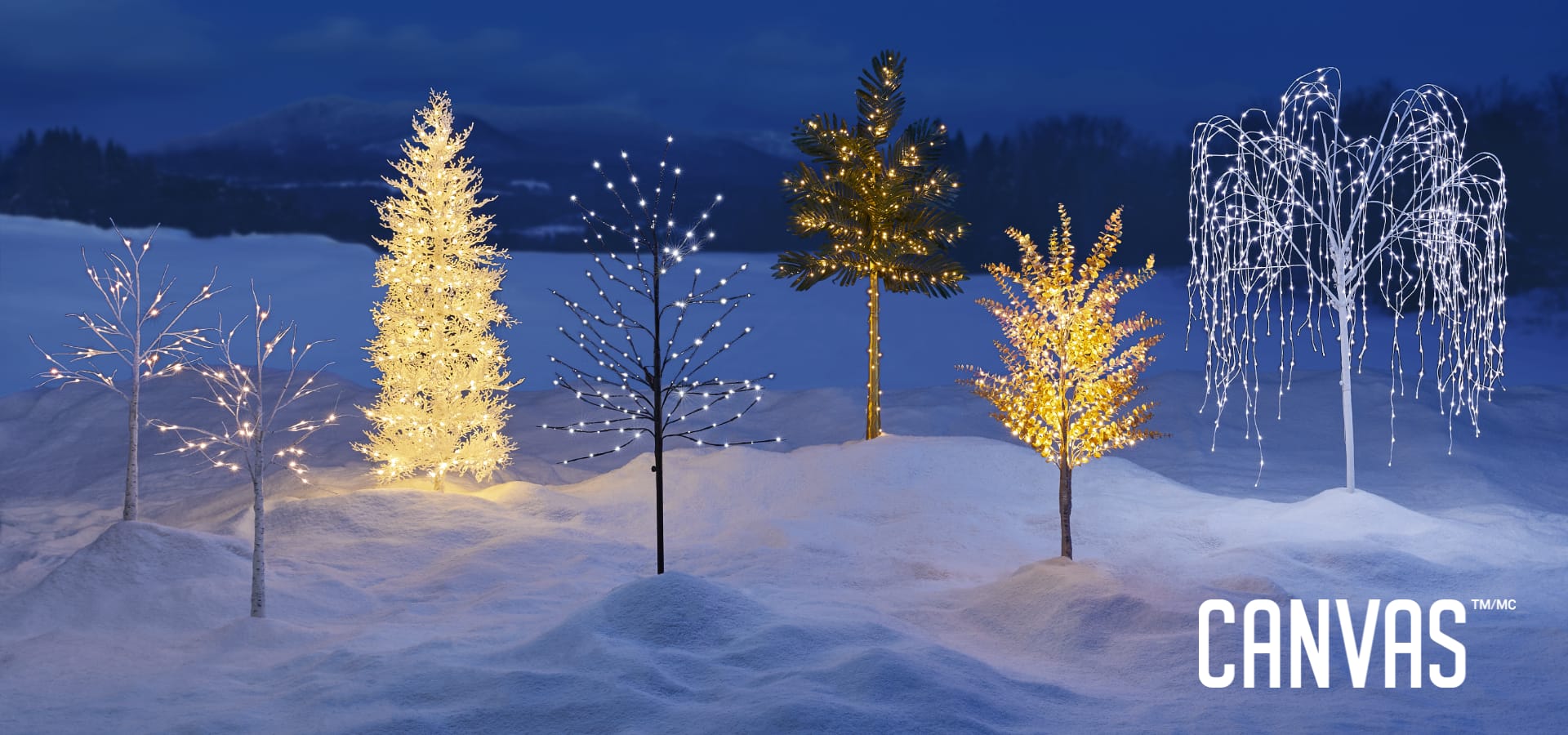 A range of CANVAS Outdoor Pre-Lit Trees on a snowy lawn.