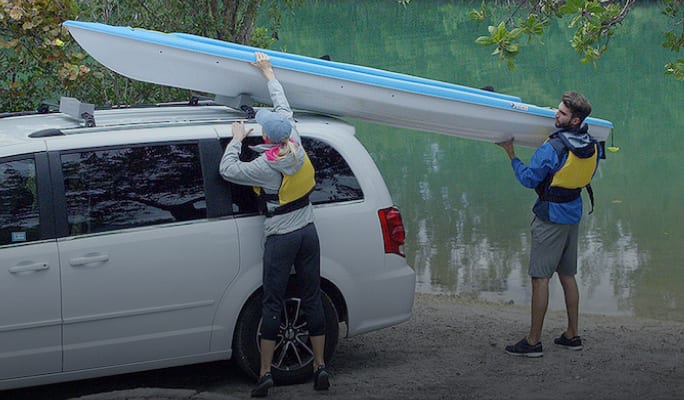 People loading kayak into a sport rack  