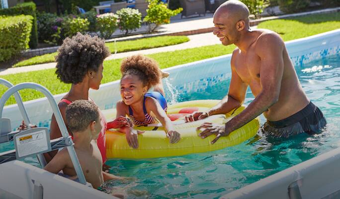 Family playing with pool floats in swimming pool  