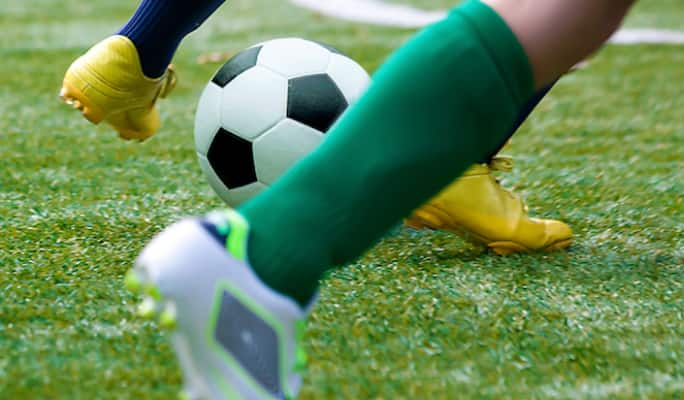 People kicking a soccer ball on field   