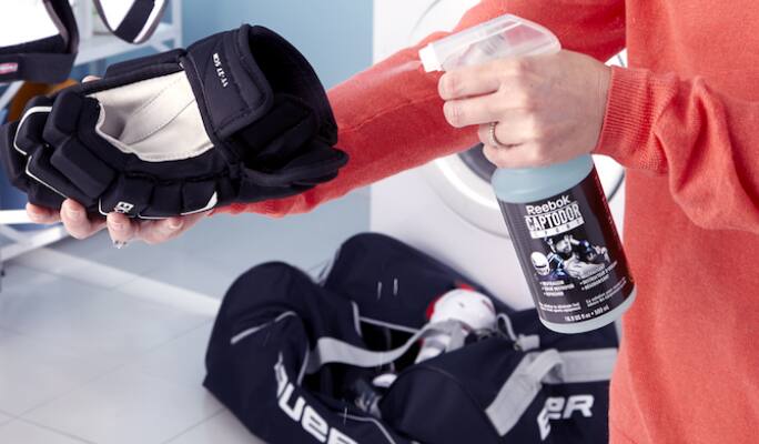 Une personne nettoyant des gants de hockey  
