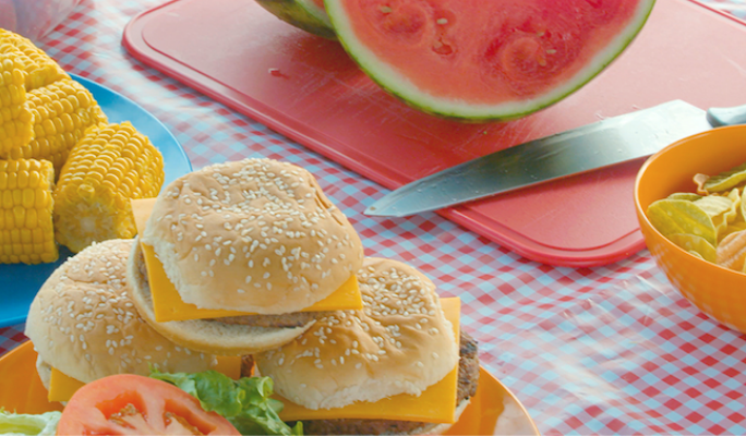 Burgers, maïs et pastèque sur une table de pique-nique  