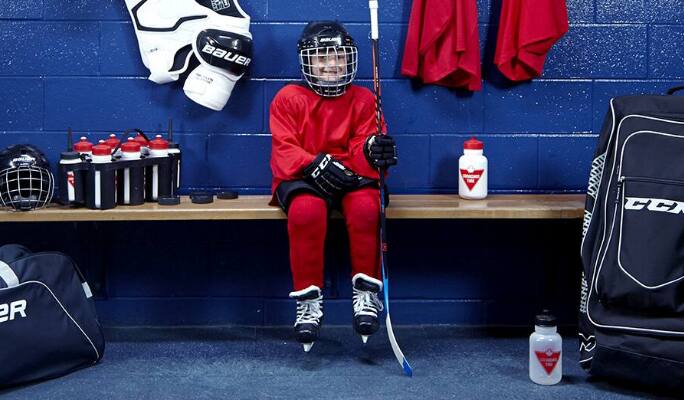 Un enfant assis sur un banc en tenue de hockey  