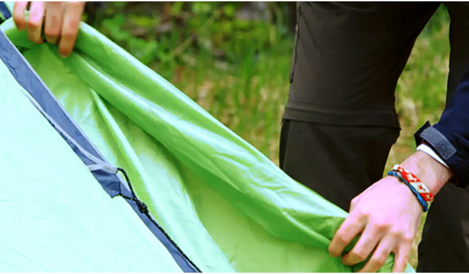 Une personne met une housse de pluie sur sa tente 