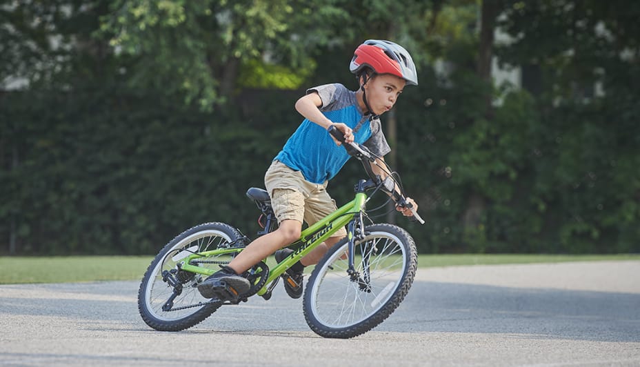 Un garçon sur un vélo vert et noir.