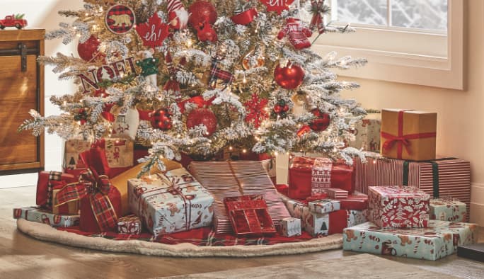 Cadeaux de Noël enveloppés avec du papier d’emballage de la collection Noël au camp CANVAS sous un sapin