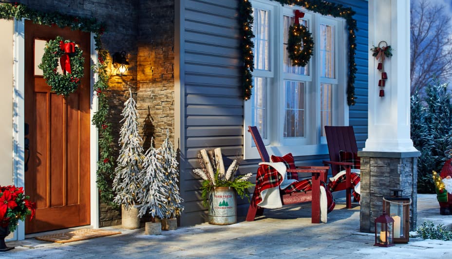Front porch of home decorated with potted trees, wreaths and garland
