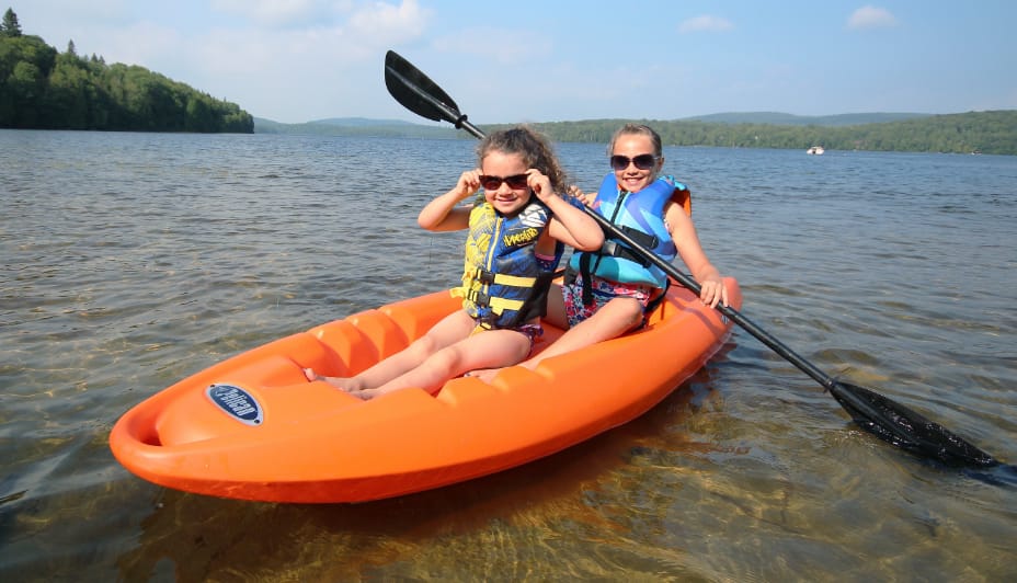 Two young girls kayaking on a lake