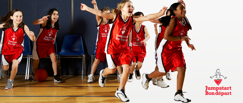 A group of girls in uniform running onto a basketball court