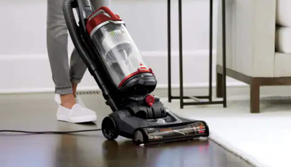 Une personne poussant un aspirateur sur un plancher en bois