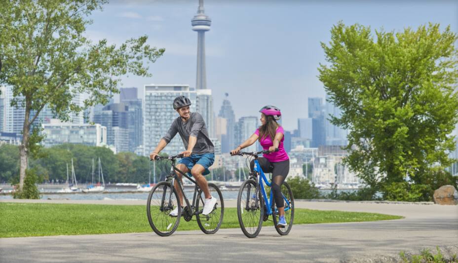 Des gens qui font du vélo avec la Tour CN en arrière-plan