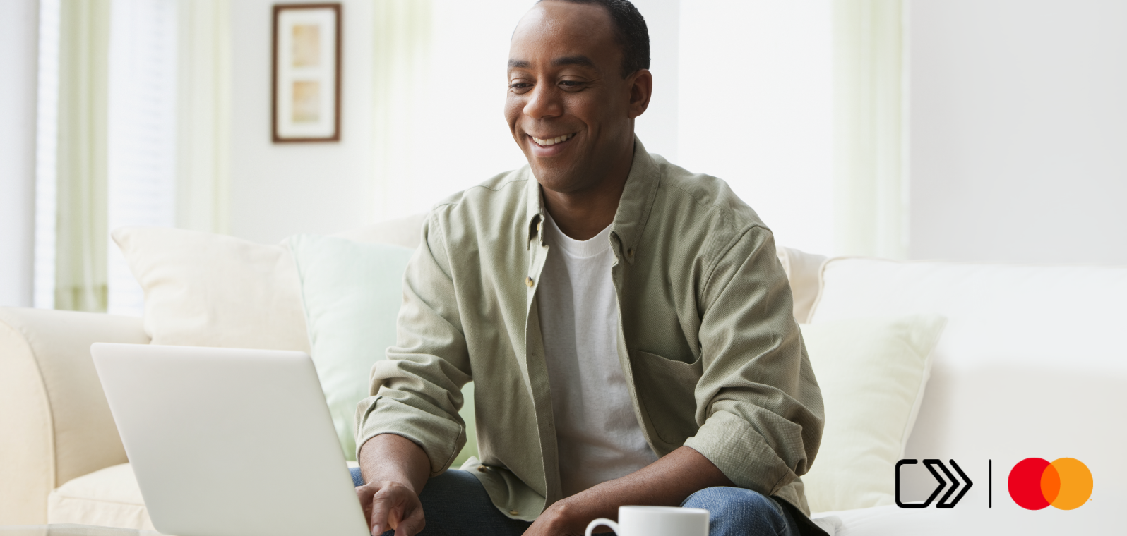 A smiling man shops online using a laptop.