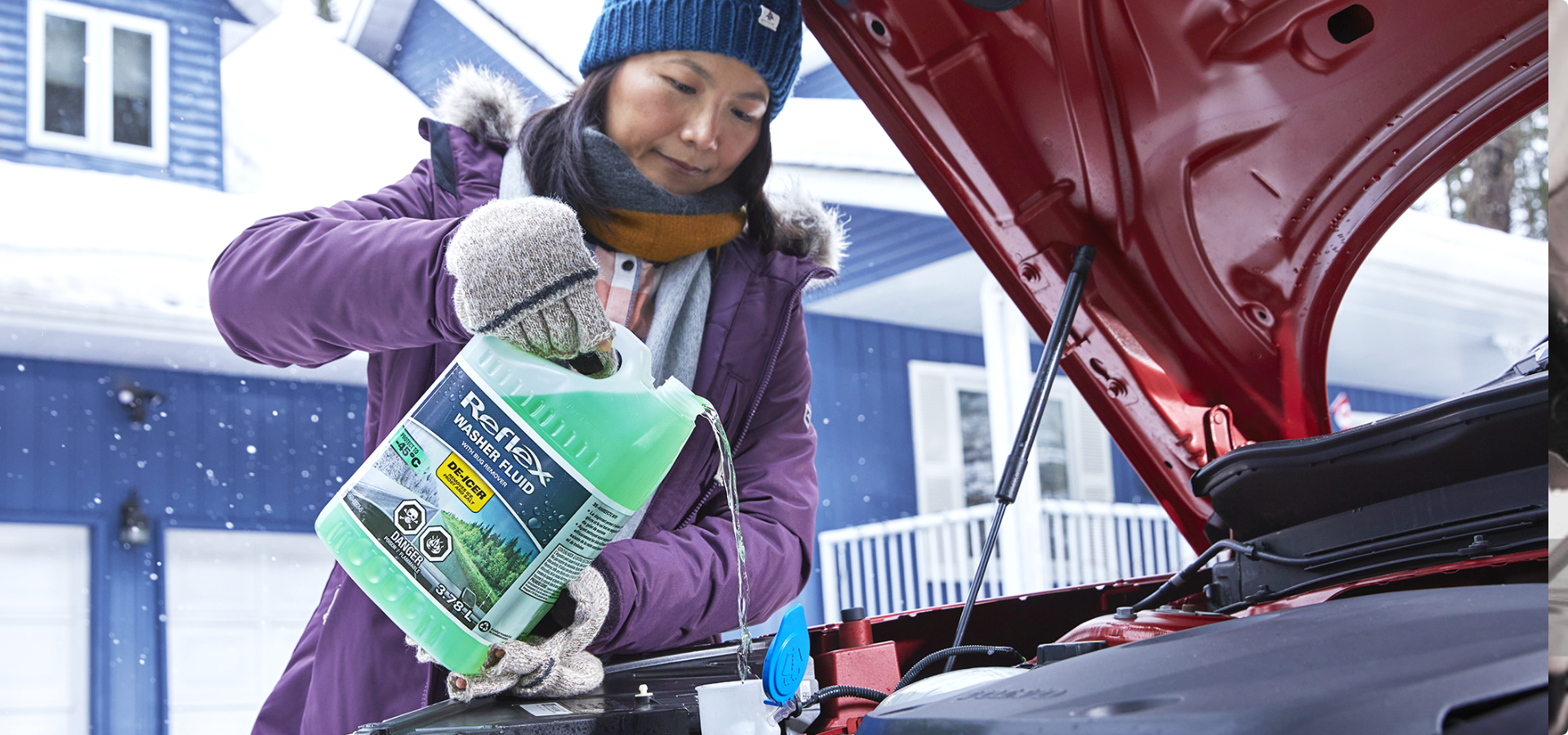 A driver pours Reflex Washer Fluid into a car’s fluid reservoir in a winter setting.