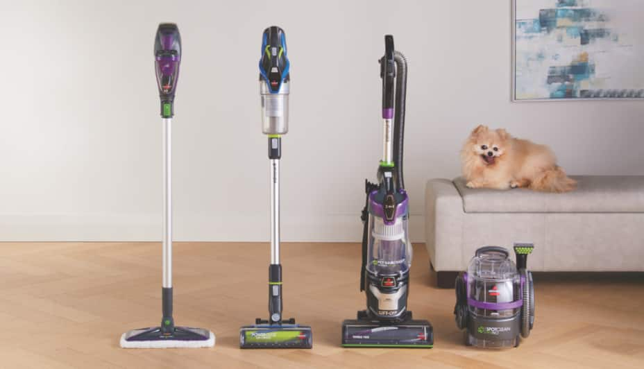 Four vacuum cleaners and a dog in a room.