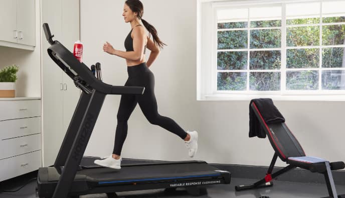 A woman runs on a treadmill indoors.