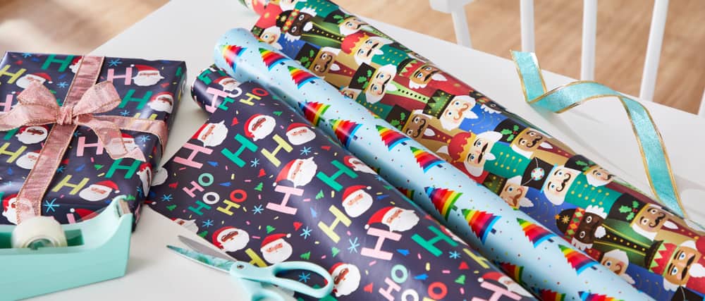 Person wrapping Christmas gifts with wrapping paper and bows