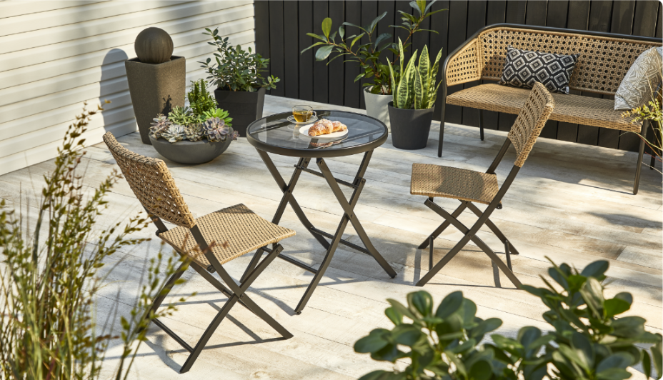  CANVAS Chambly Collection bistro chairs, a table and a bench on a patio with plants.