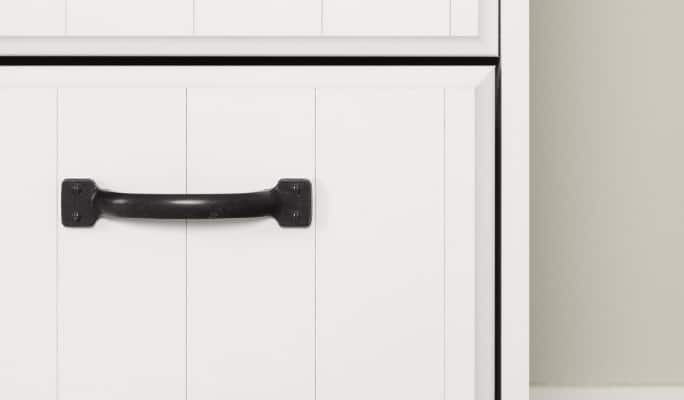 A black drawer pull mounted on the front of a white drawer.