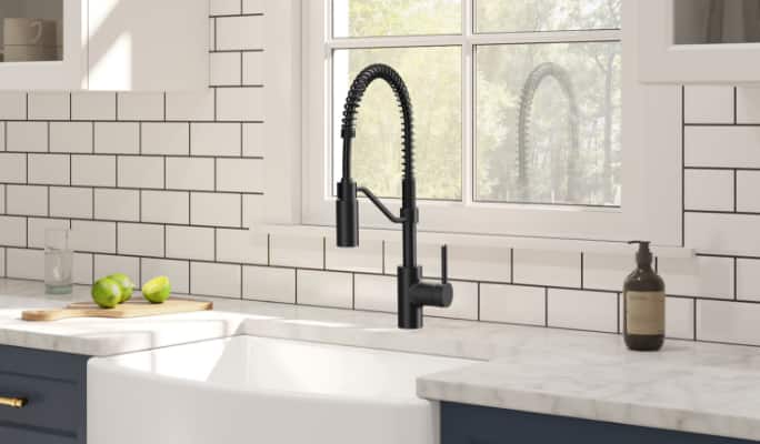 A matte black Danze Jasper Single Handle Pull Down Kitchen Faucet in a white-tiled kitchen.