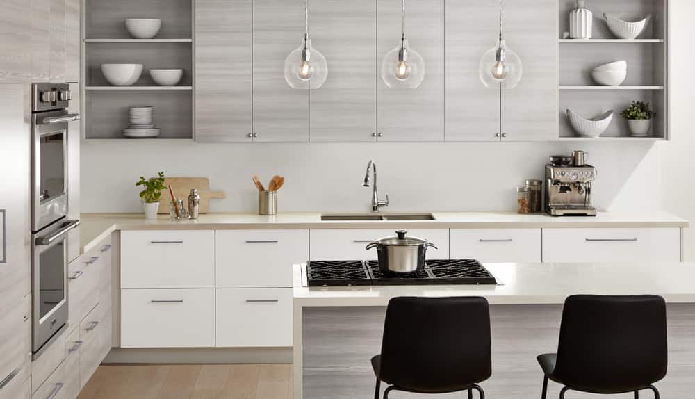 A stylish white-and-grey kitchen with chrome design elements, including pendant chandeliers, faucets and cabinet pulls.