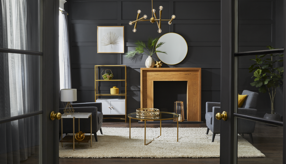 A black living room with gold furniture and design elements, including a chandelier, table lamp and coffee table.