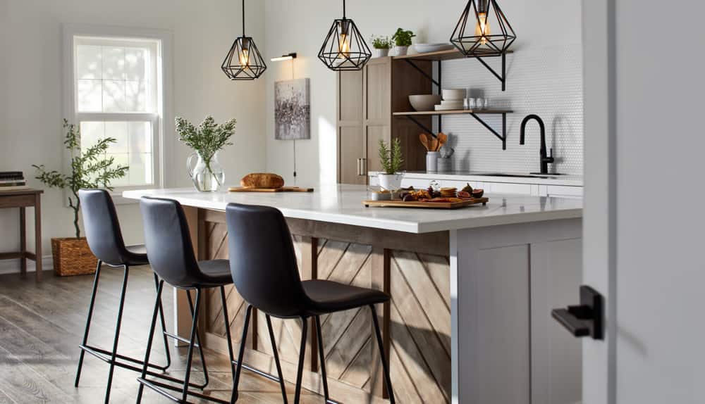 A modern-look light-grey kitchen accented with black faucets, chandeliers and chairs.