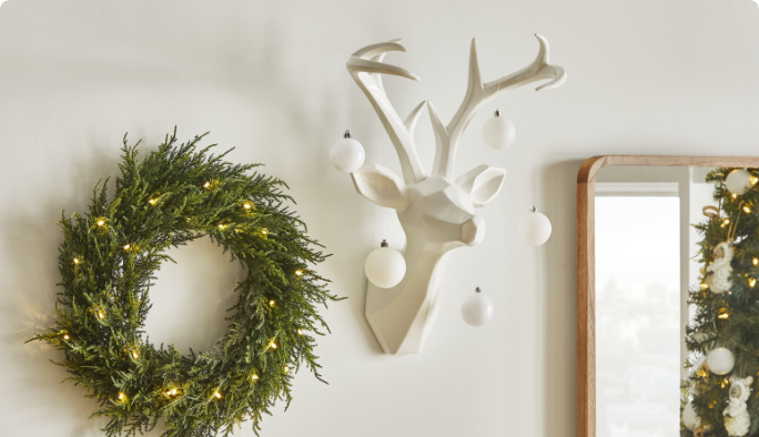 CANVAS resin reindeer head and pre-lit wreath on a wall