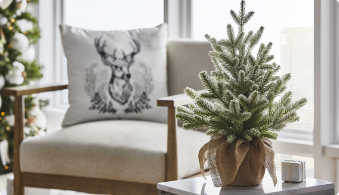 CANVAS tabletop tree beside chair with reindeer cushion