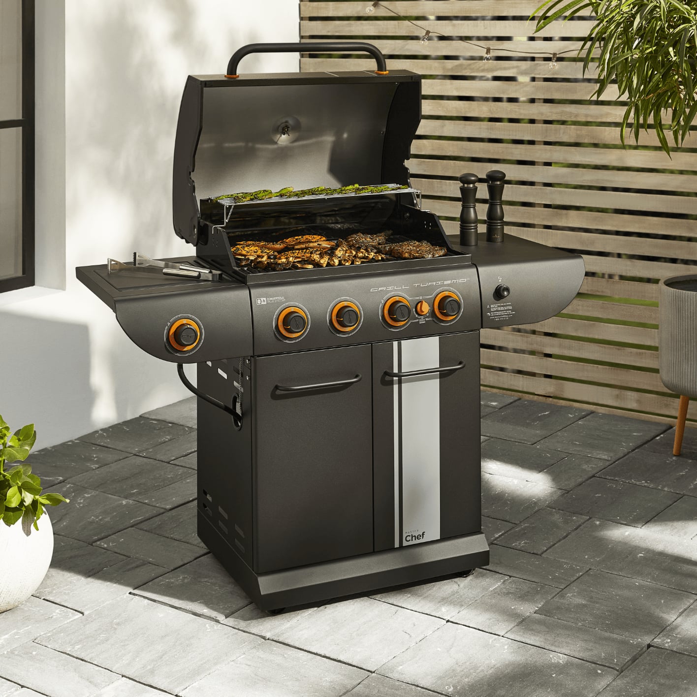 Food grilling on a MASTER Chef Turismo Convertible Propane BBQ on a patio.
