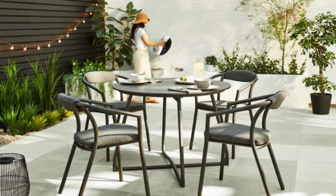A CANVAS Trent Dining Set with dishes and drinks in a backyard.