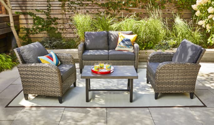  CANVAS Brenton Collection Loveseat, armchairs, ottoman and side tables on a patio. 