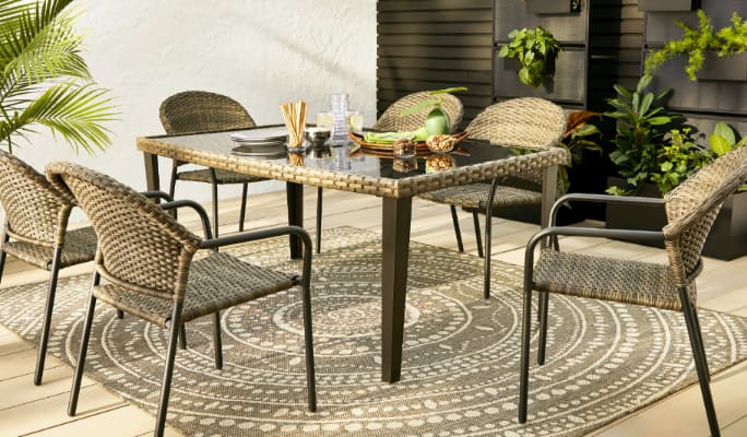 CANVAS Brenton Collection barrel chairs and glass top dining table on a patio. 
