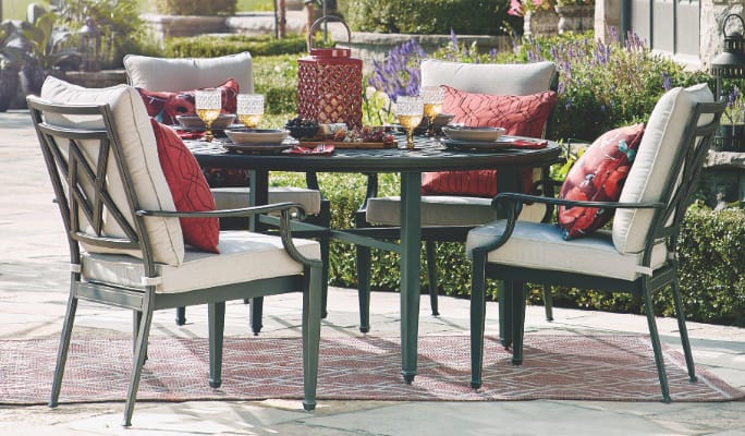 A CANVAS Coventry Hills dining table and cushioned chairs in a backyard. 