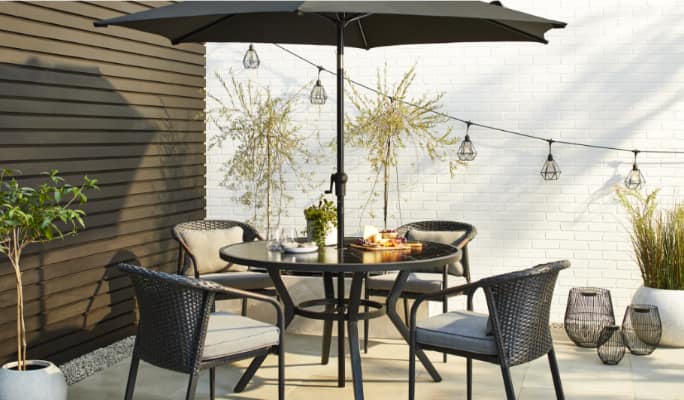 CANVAS Jasper Dining table and chairs with an umbrella on a patio.