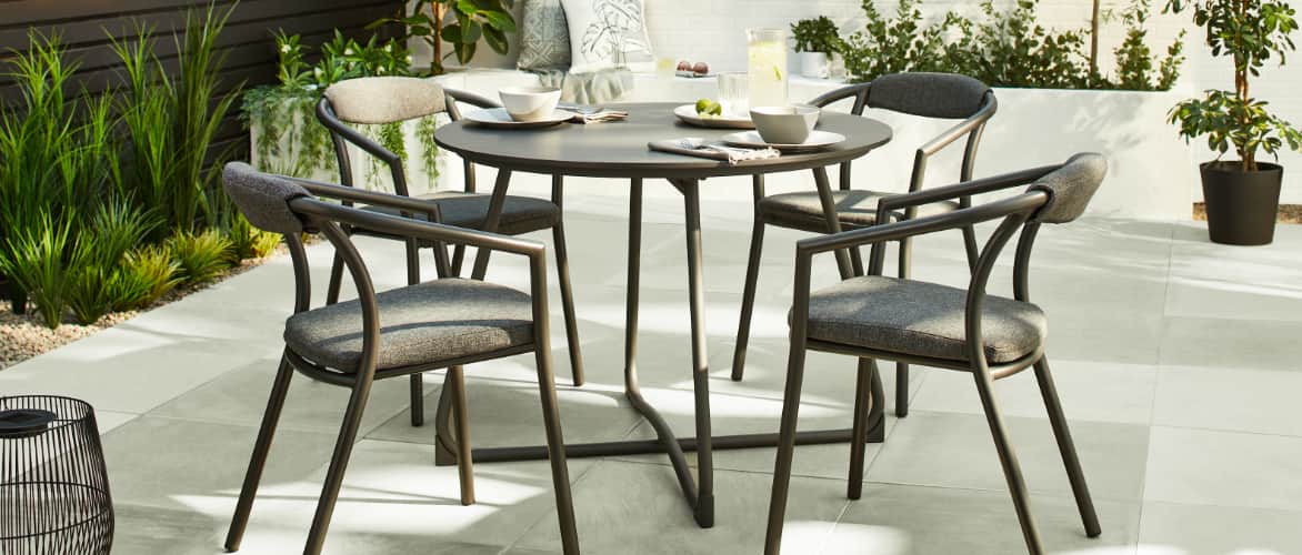 A CANVAS Trent 5-Piece Dining Set with dinnerware on a patio. 
