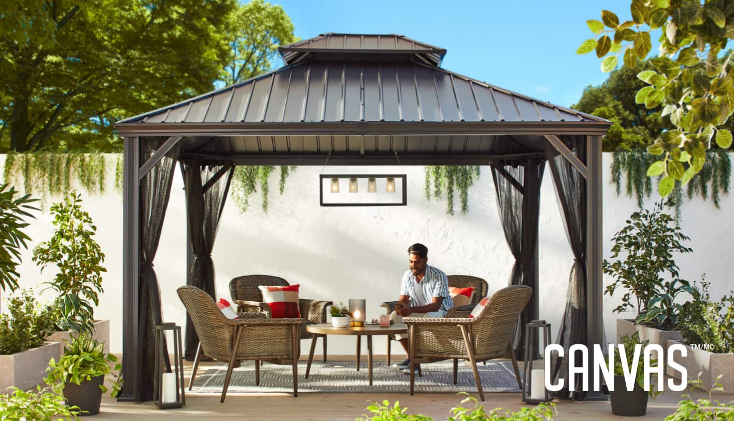 Un abri de jardin CANVAS Skyline installé sur une terrasse d’arrière-cour avec des chaises longues, une table et une moustiquaire. 