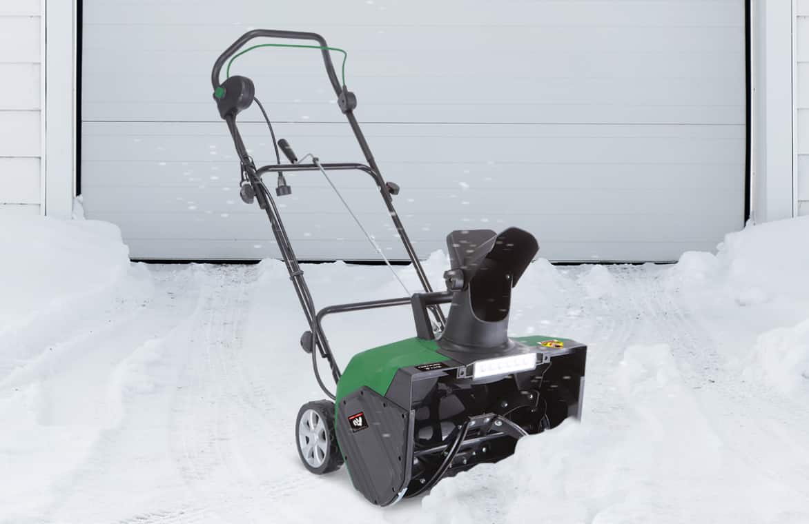 Electric snowblower by snowy driveway.