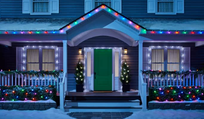 A house decorated with glowing white and multicoloured Christmas lights. 