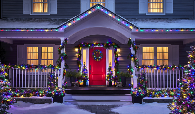 A house and yard decorated with multicoloured, glowing Christmas lights. 